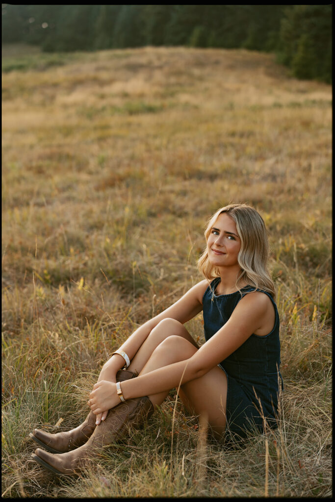 Portrait of a girl sitting in the grass wearing a denim dress