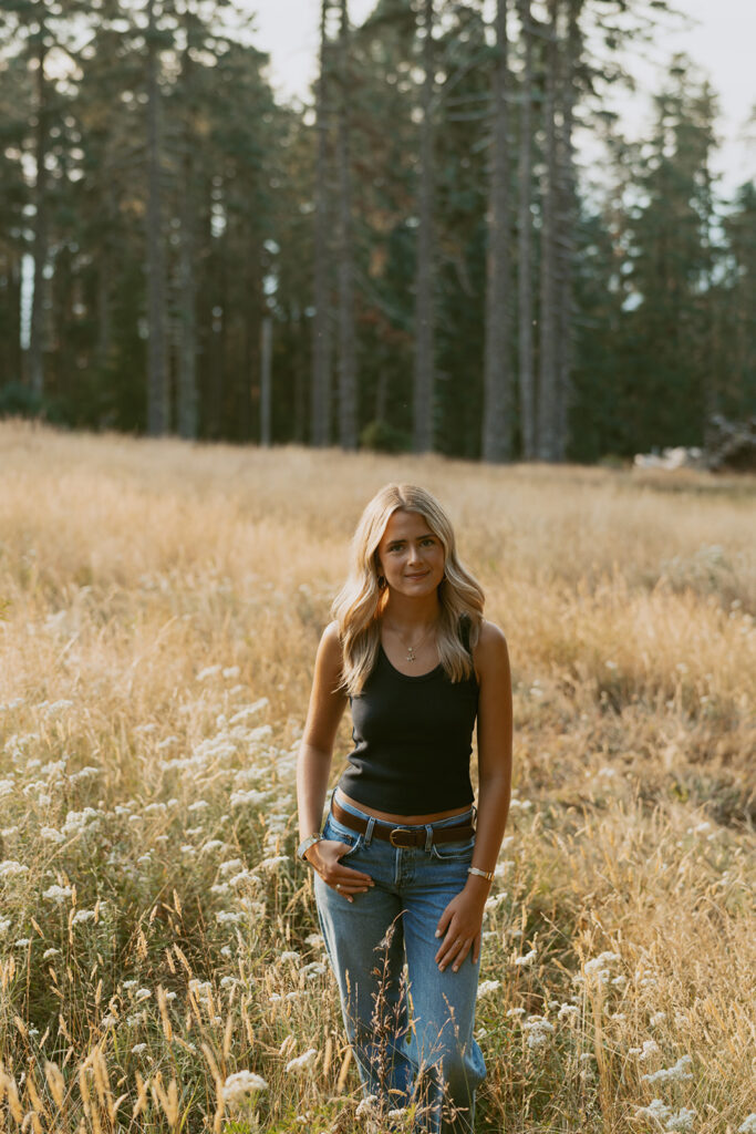 Girl standing in wildflowers wearing a black tank and jeans