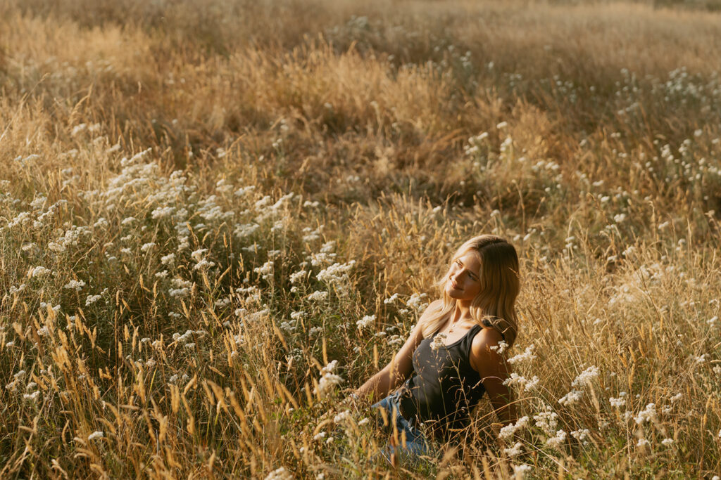 Girl sitting in wildflowers at golden hour