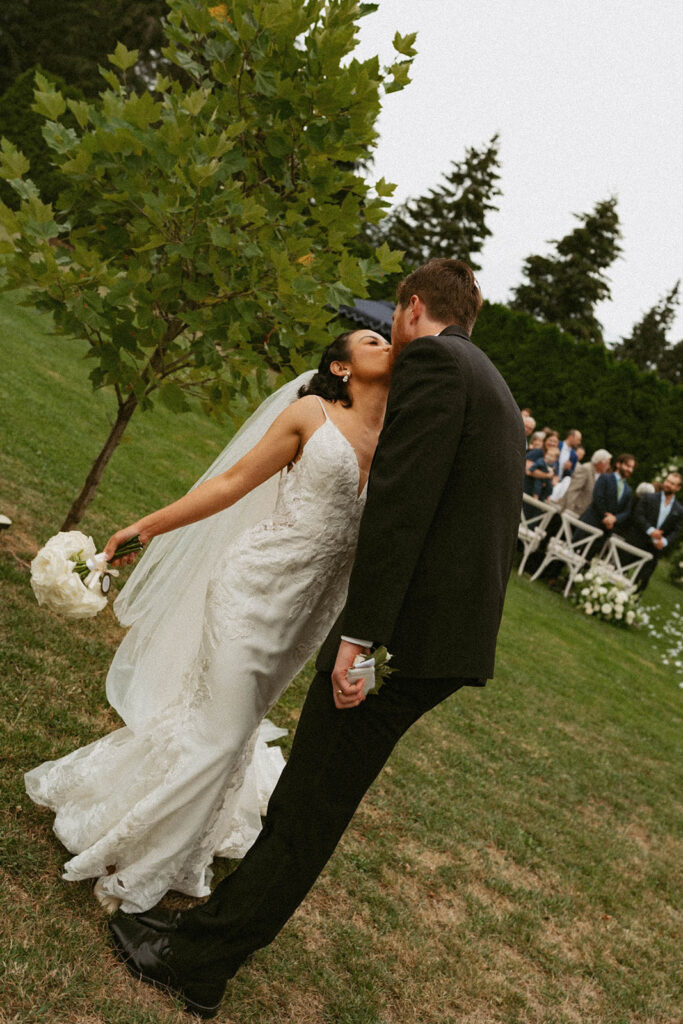 Couple kissing outdoors after wedding ceremony