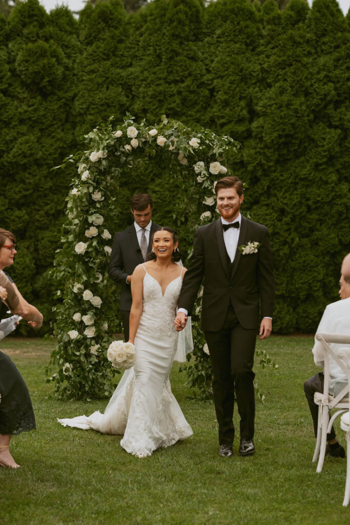 Bride and groom walking hand in hand down aisle