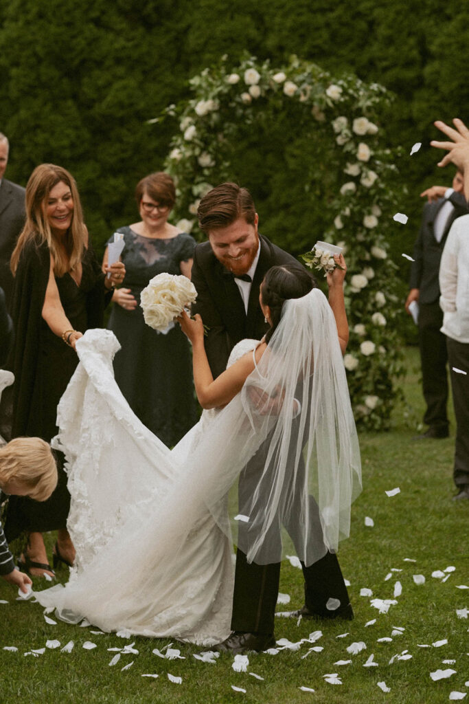 Groom dipping bride under floral arch