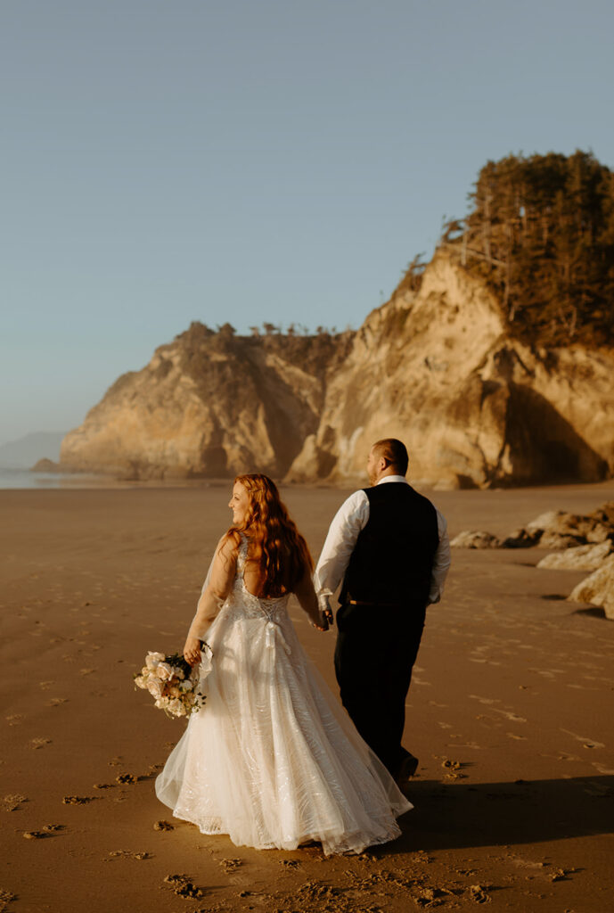 Couple walking along Oregon beach at golden hour
