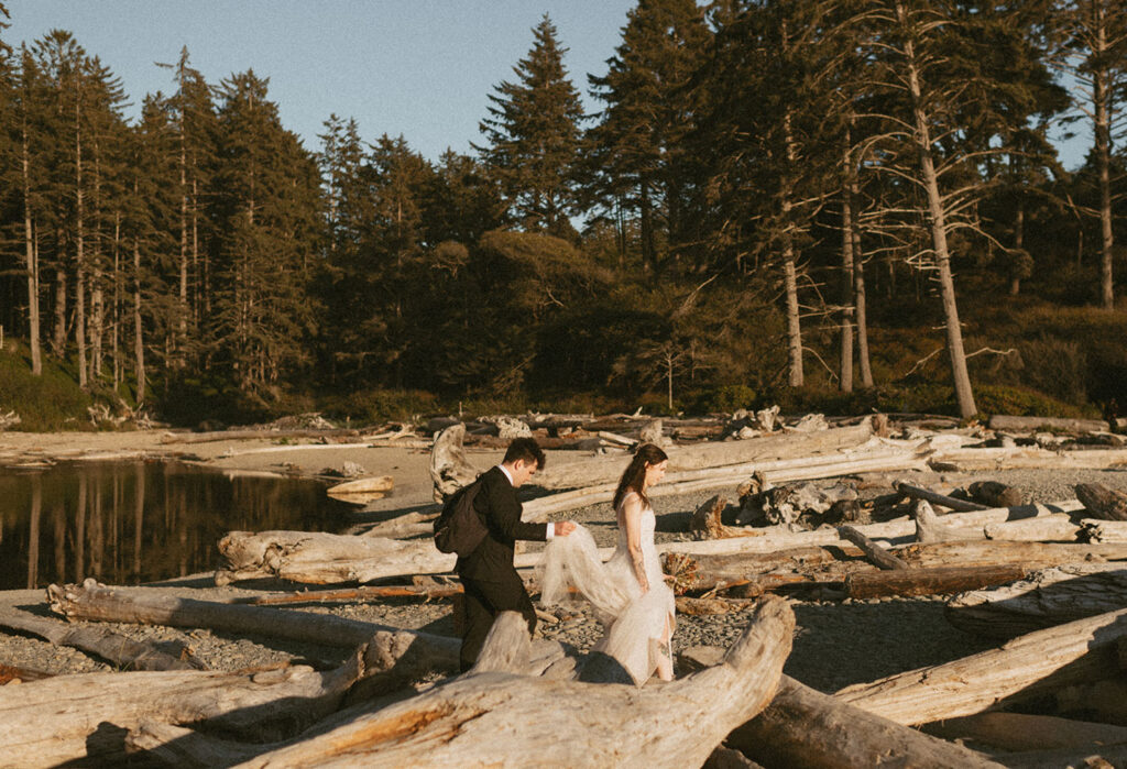 Couple walking on Oregon beach among driftwood during elopement