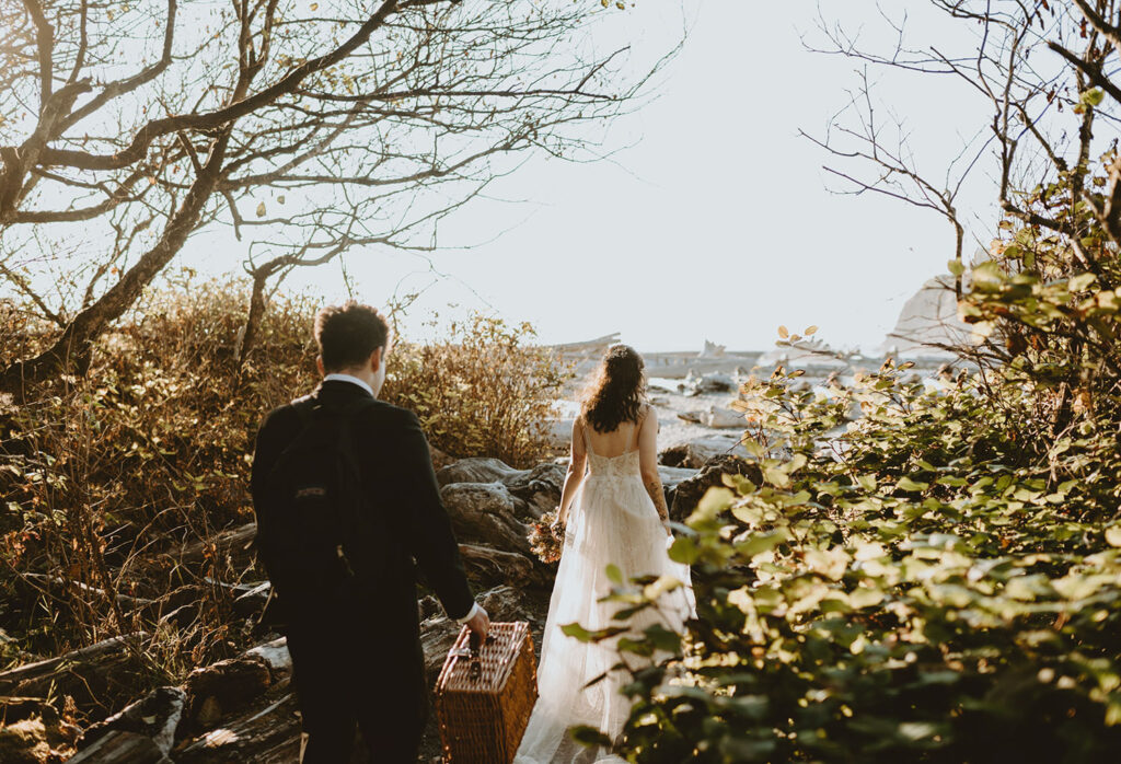 Bride and groom walking through forest path toward Oregon coast
