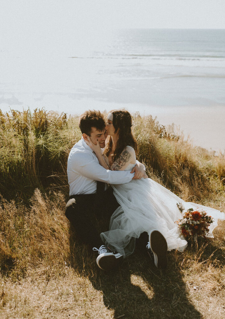 Couple sitting in the grass overlooking the Oregon coast during elopement