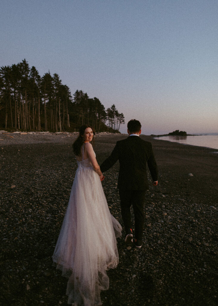 Couple holding hands at sunset on rocky Oregon shoreline