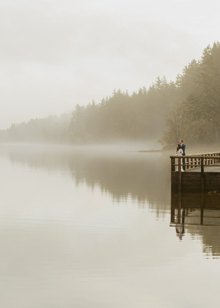 Couple standing on dock above foggy Oregon lake