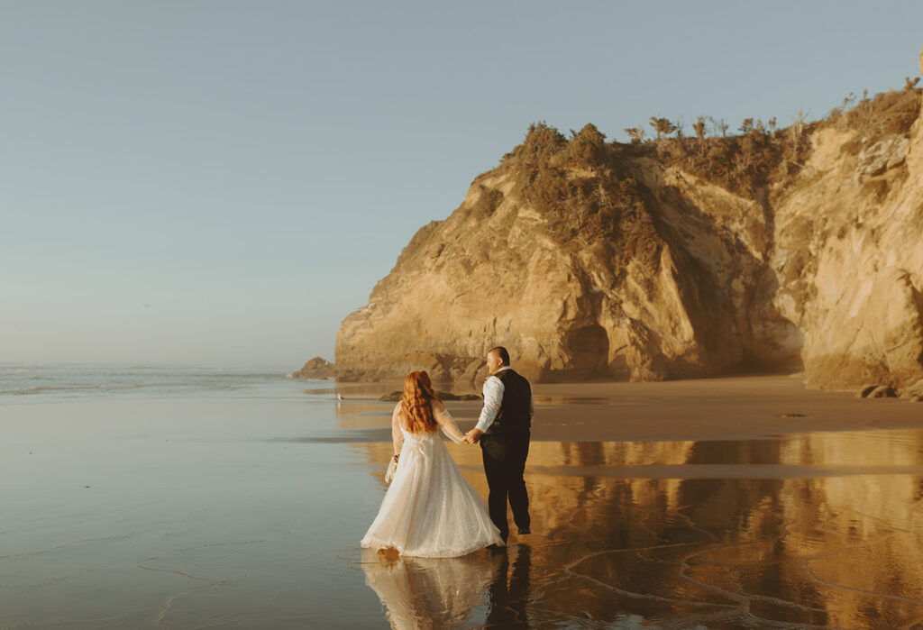Couple holding hands walking along golden Oregon cliffs