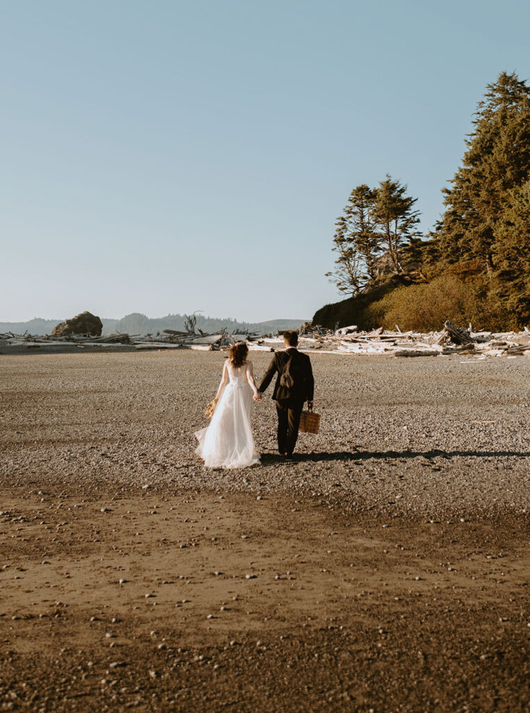 Bride and groom walking hand in hand on rocky Oregon beach