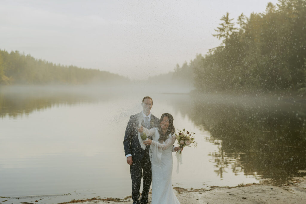 Couple laughing as water splashes during lake elopement in Oregon