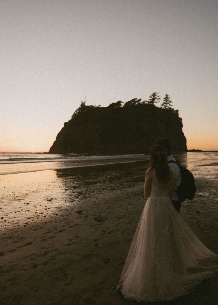 Bride and groom watching sunset over Oregon coastline