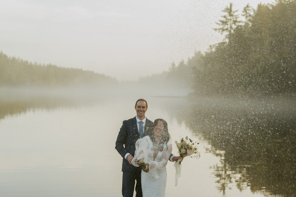 Couple smiling as water splashes during Oregon elopement by the lake