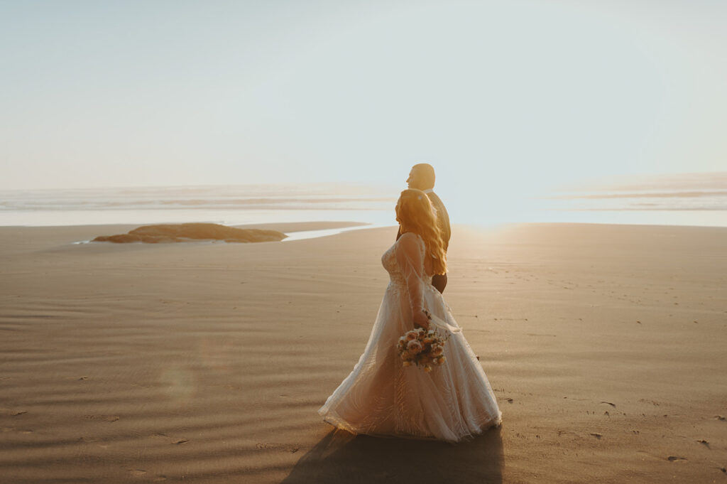 Bride and groom walking along the Oregon coast at sunset