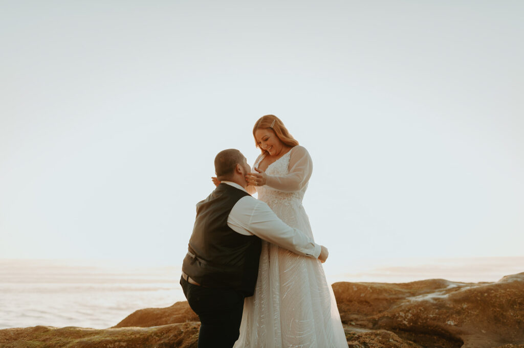 Groom lifting bride on seaside rocks at Oregon coast