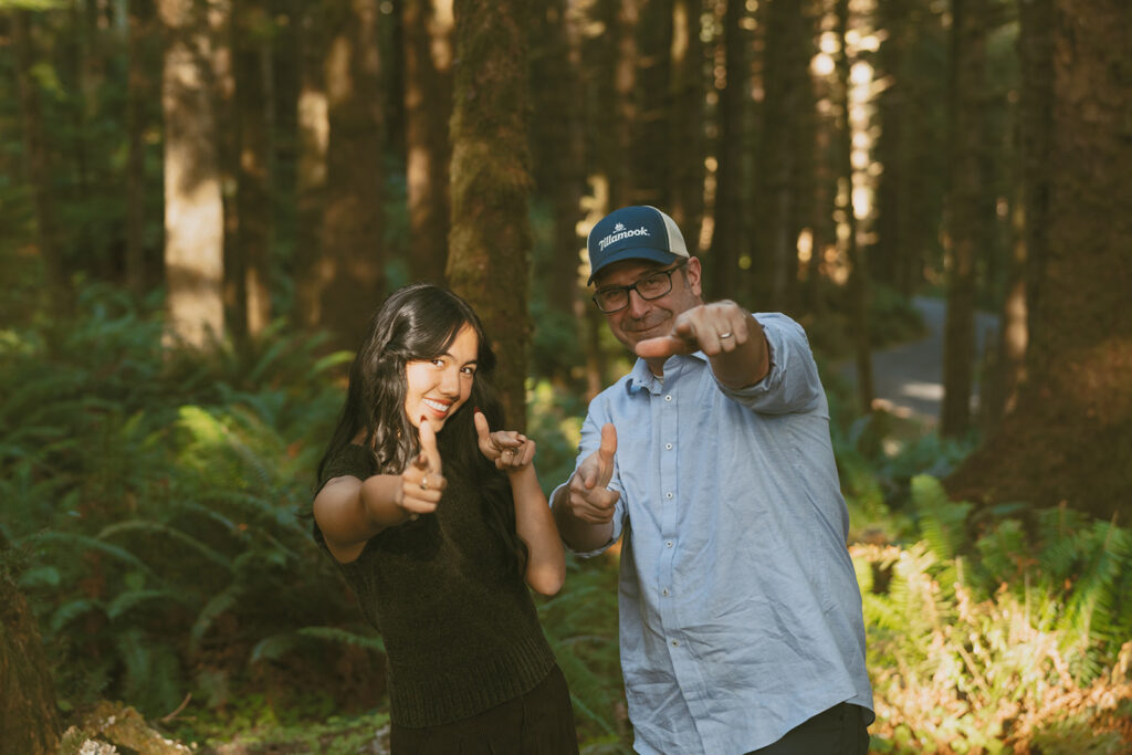 Woman and man pointing playfully at camera in forest