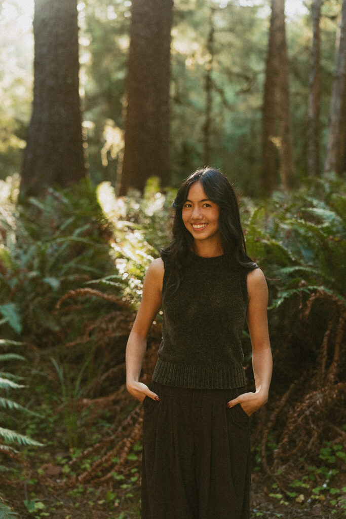 Woman in dark outfit smiling in forest