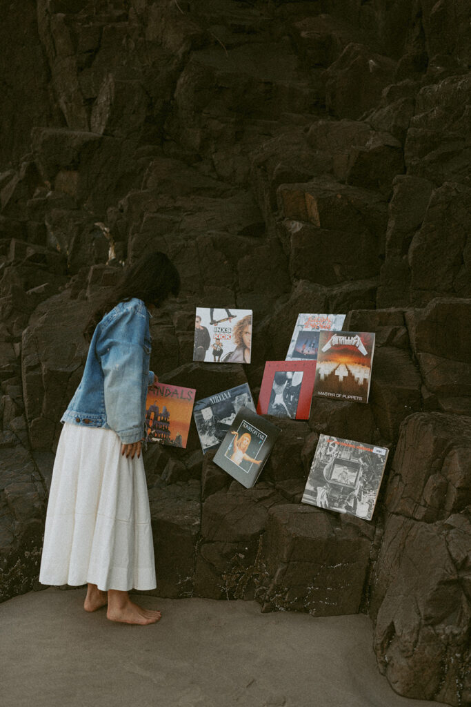 Woman in white dress and denim jacket looking at vinyl records on rocks