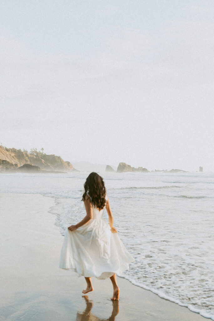 Woman in white dress walking by the ocean shore