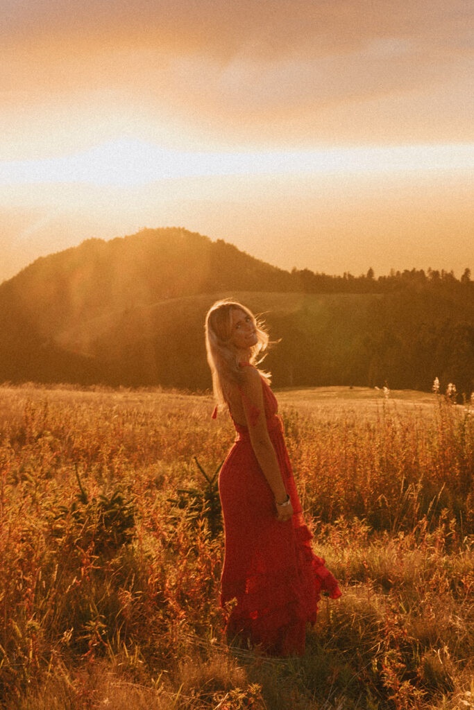 A senior girl looks back in warm sunset light