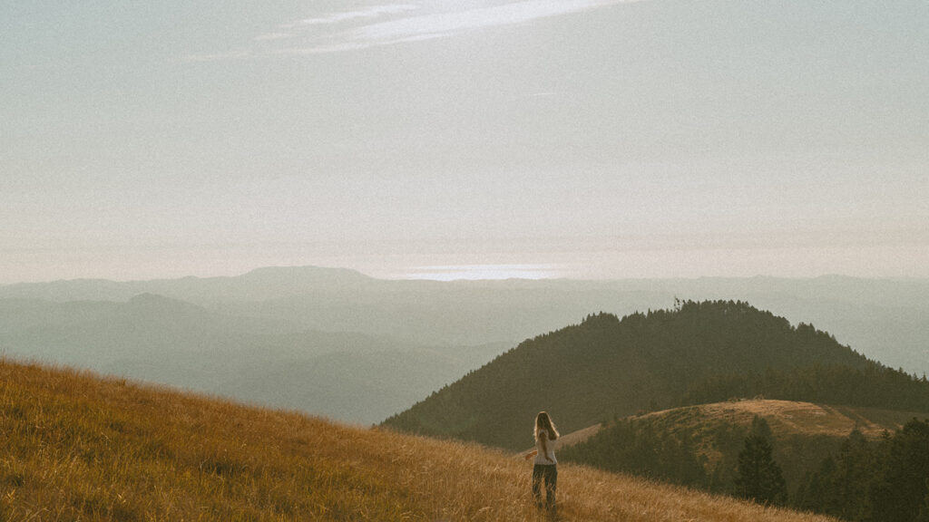 A senior walks on a hilltop at sunset with distant mountains