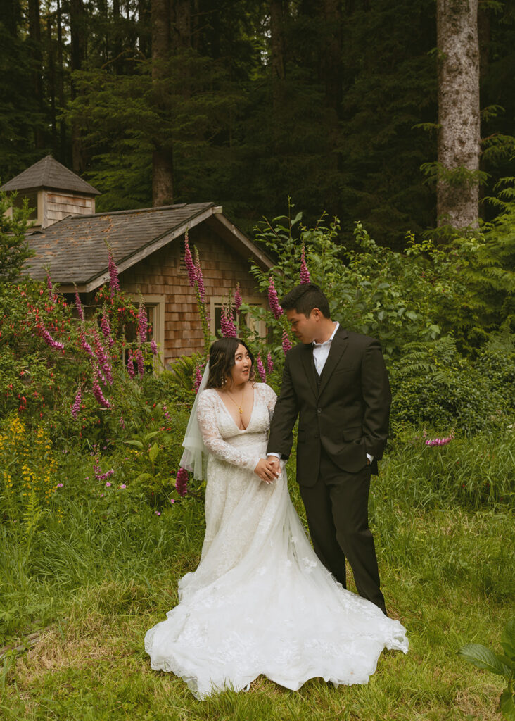 Bride and groom holding hands in front of a cottage garden