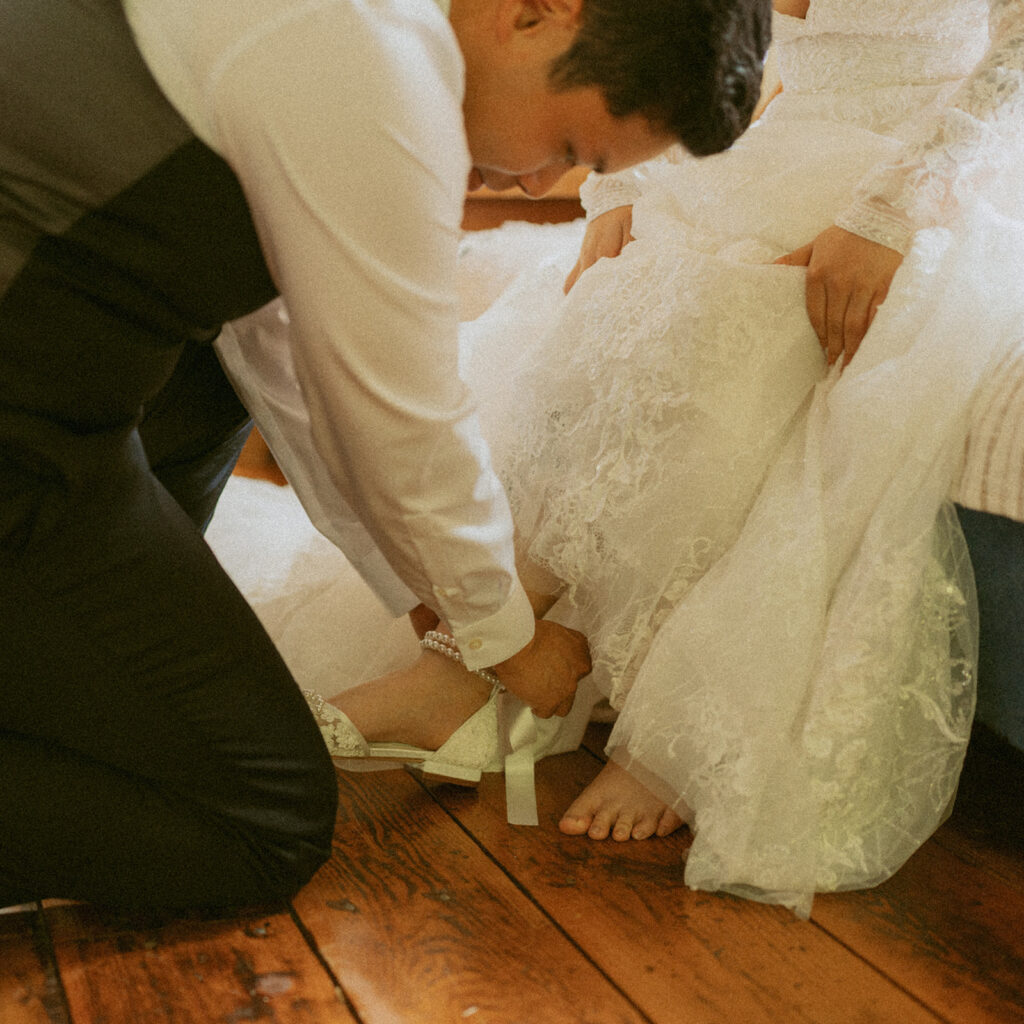 Groom fastening the bride’s shoe strap