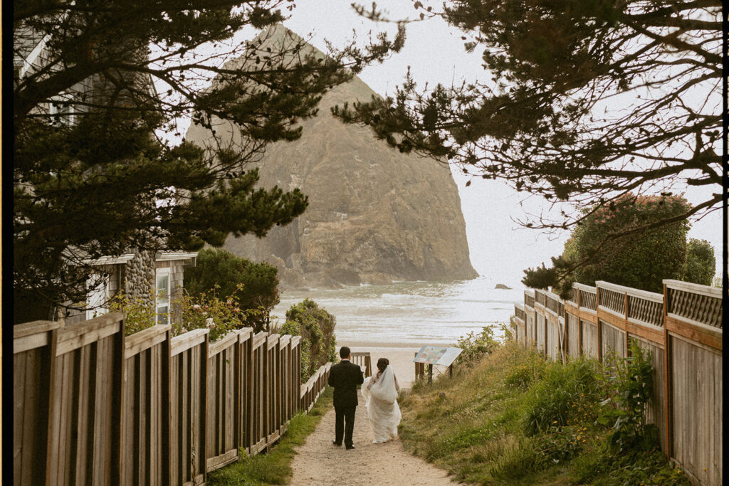 Couple walking down a sandy path toward Haystack Rock