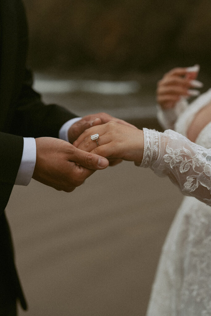 Close-up of hands showing wedding rings on the beach