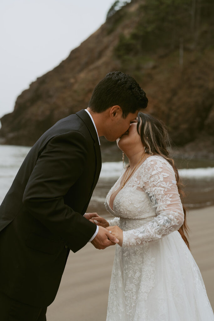 Bride and groom kissing on the beach near the rocks
