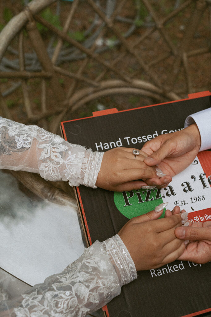 Close-up of hands with wedding rings on a pizza box