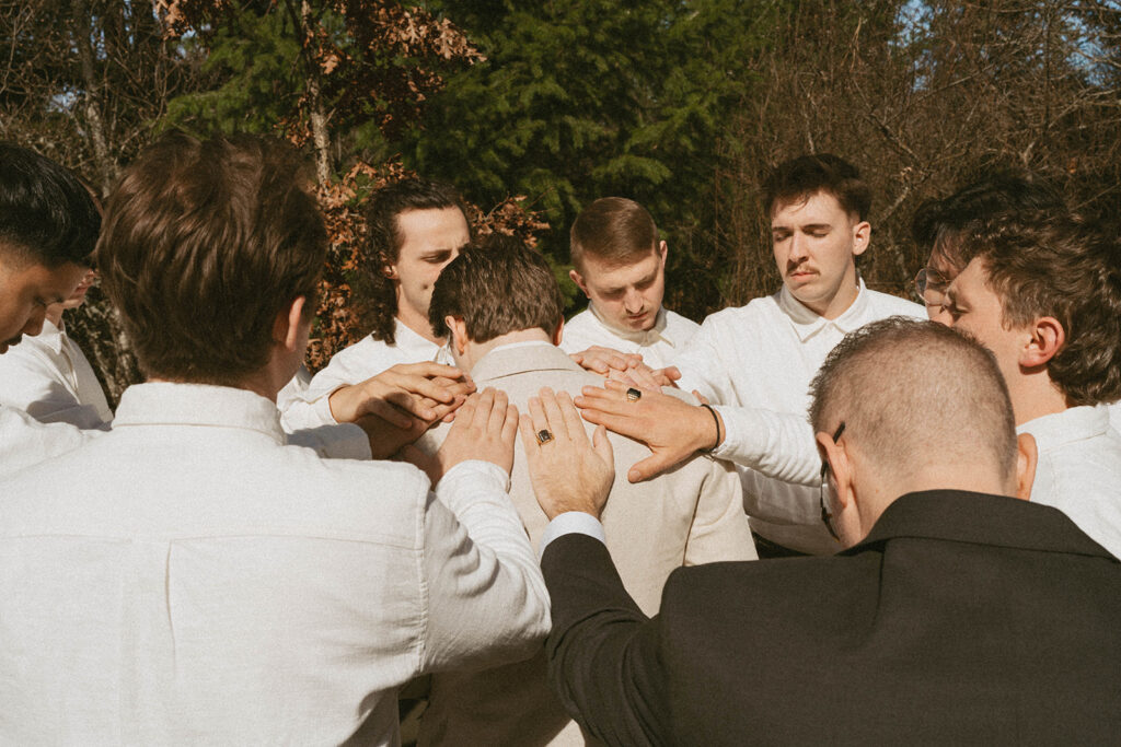 Groomsmen praying together before ceremony, Washington state wedding