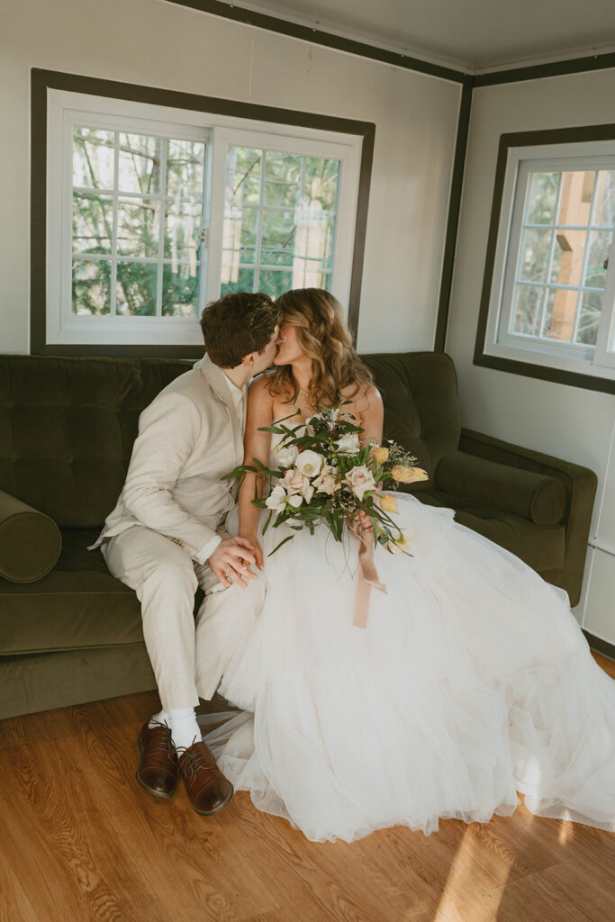 Couple kissing on couch indoors, intimate wedding moment