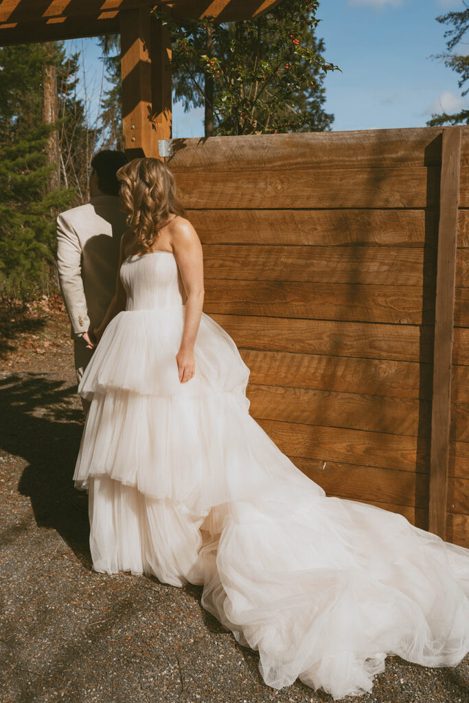 Bride and groom first look behind wooden wall