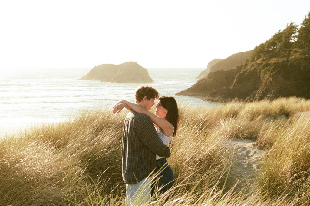 Couple embracing in coastal grass by the ocean