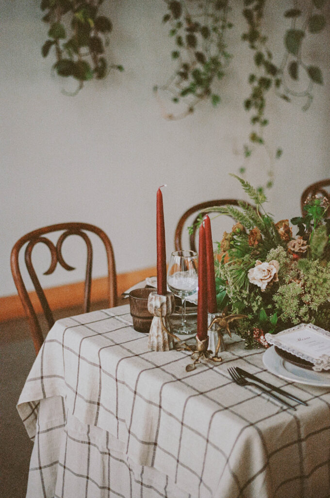 Table with plaid linen, red candles, and greenery