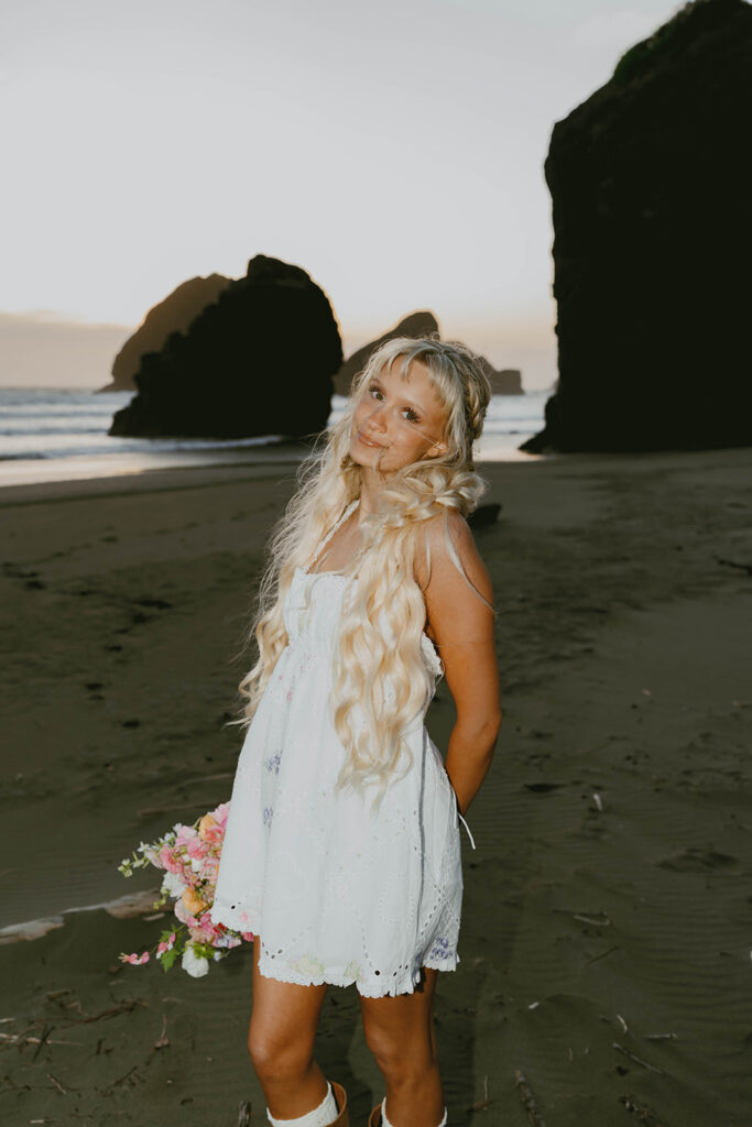 Senior posing on the beach with a bouquet
