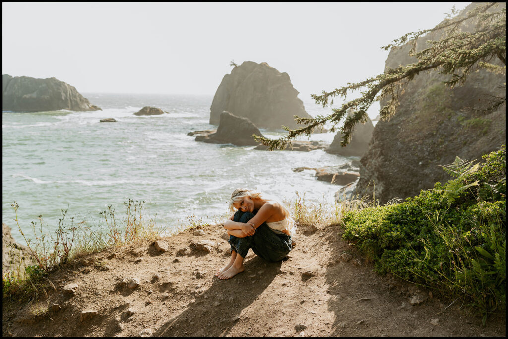 Senior sitting barefoot above the rocky coastline