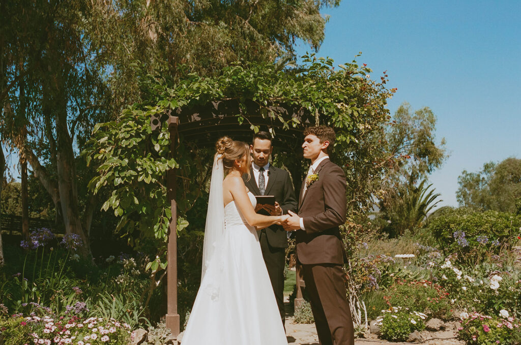 Couple exchanging vows beneath a garden arch