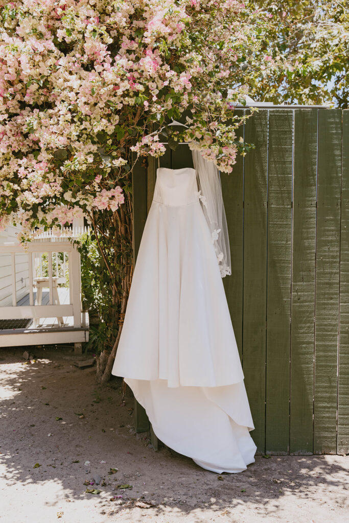 White dress hanging beside flowering vines