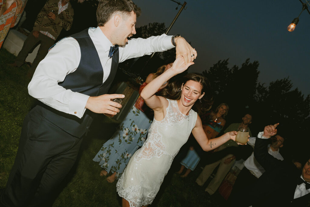 Groom twirling the bride on the dance floor during their wedding reception